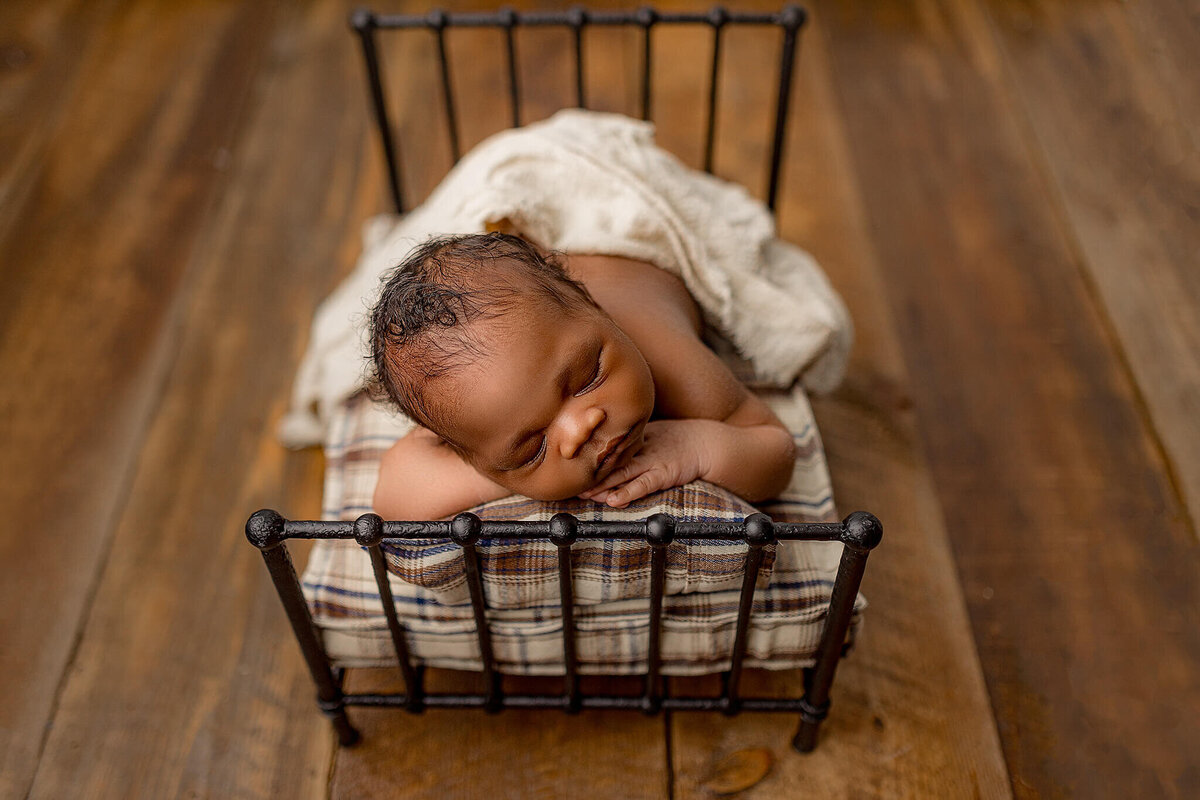 baby posed on newborn bed prop