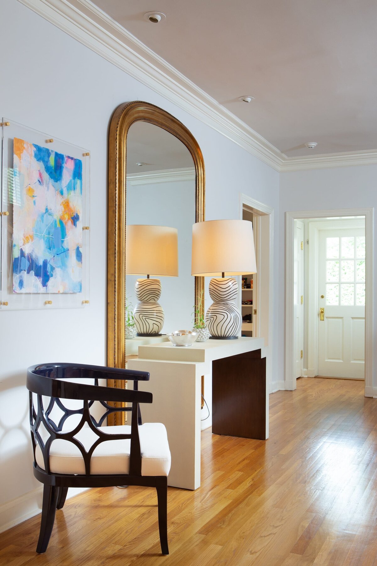 the keeping room interiors alta entry table with black chair and rounded gold mirror