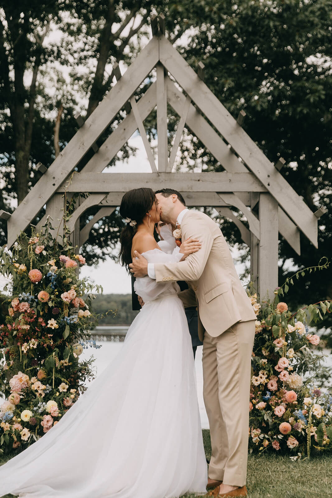 30.wedding-ceremony-bride-groom-first-kiss-under-wooden-arch-floral-decor