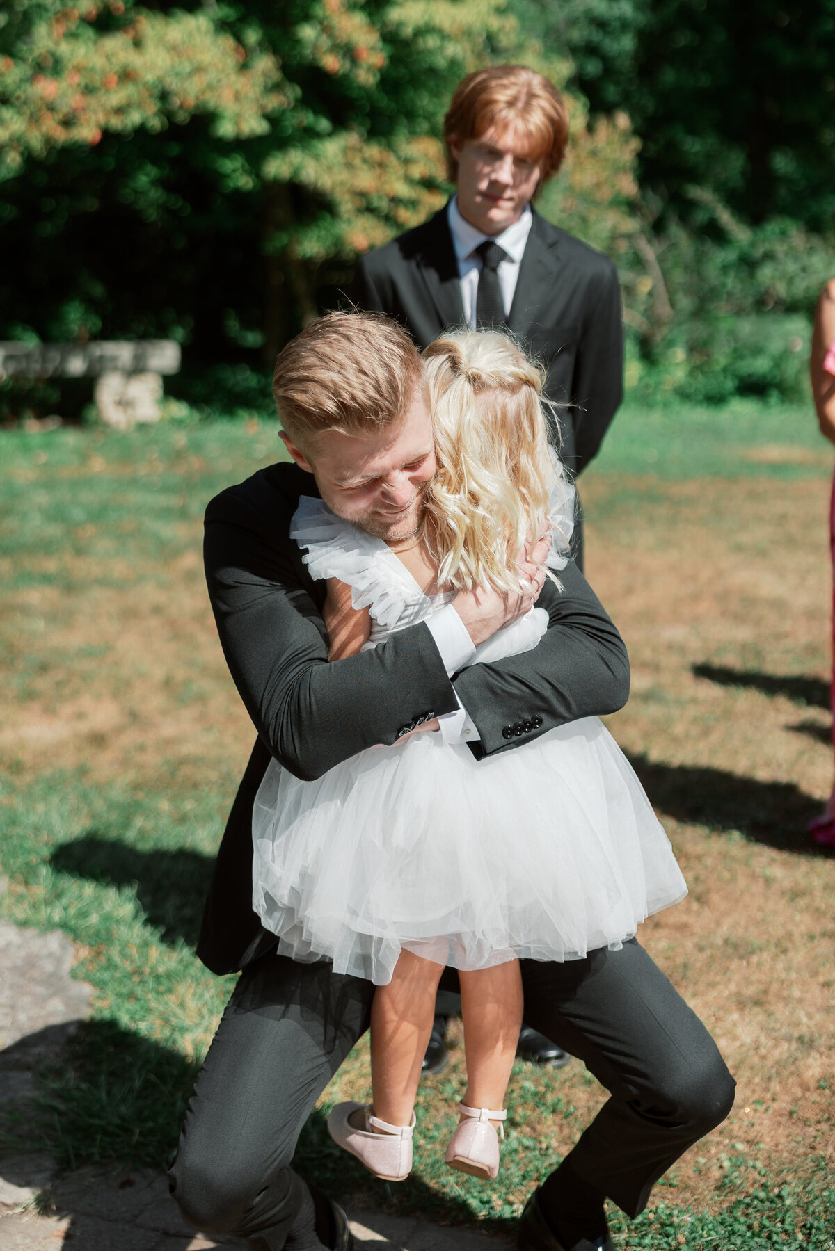 Groom hugs flower girl at Dayton wedding, a moment captured by Philadelphia wedding photographer.