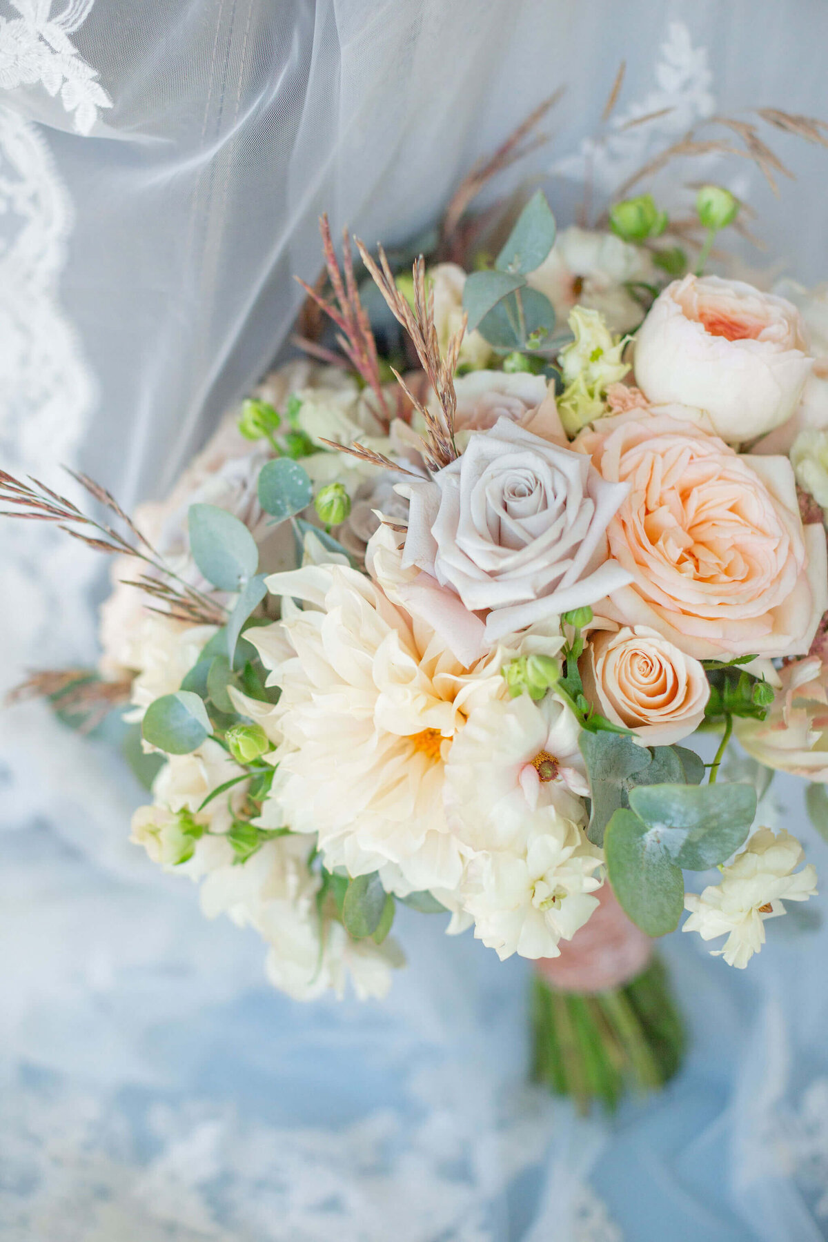 bridal bouquet rests on the lace of a bride's veil