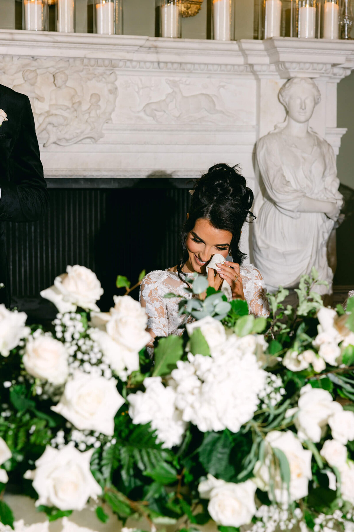A wedding photo of a bride wiping happy tears from her eyes during a speech at her wedding a Luttrellstown Castle