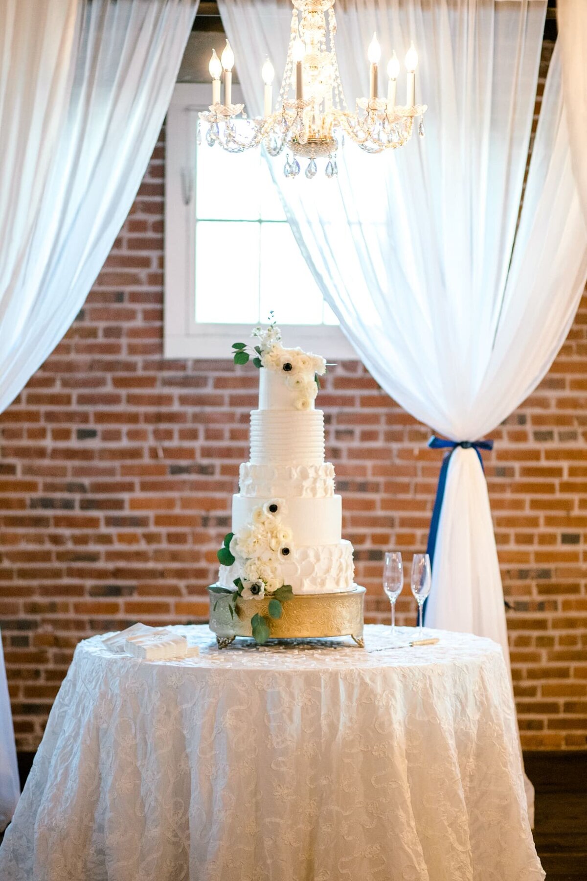 Tall white wedding cake in front of brick wall