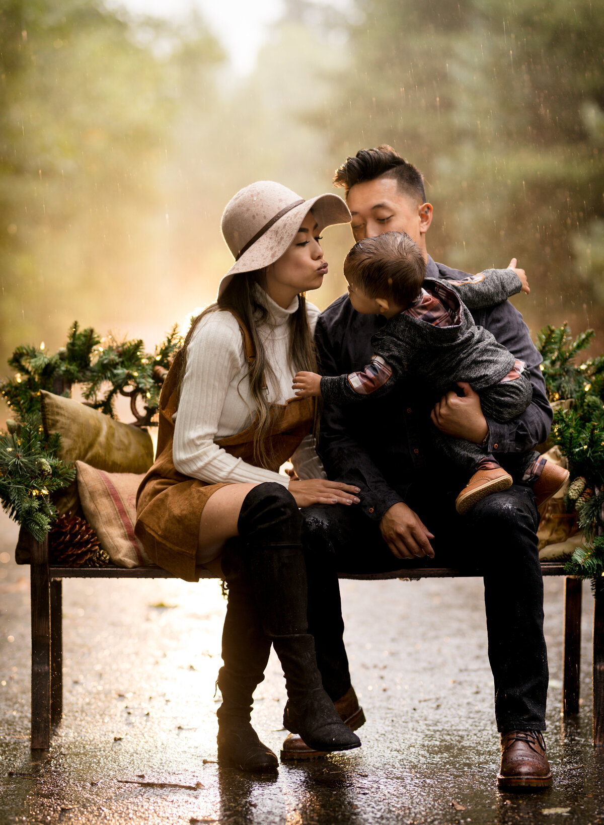 glowy-chrismtas-family-photoshoot-mom-kissing-baby-in-rain
