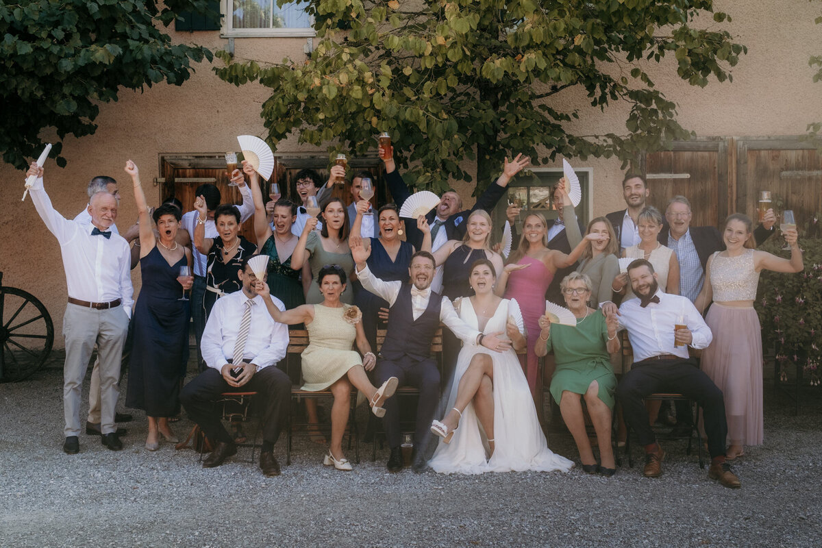 Dieses Gruppenfoto zeigt die gelöste Stimmung des jubelnden Hochzeitspaares mit ihren Gästen mit Fächern.