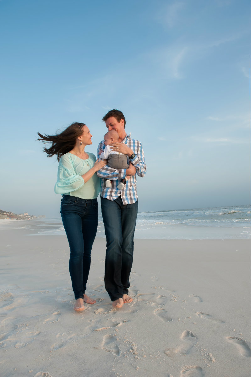 Couple with baby walking on the beach in Seagrove on 30a