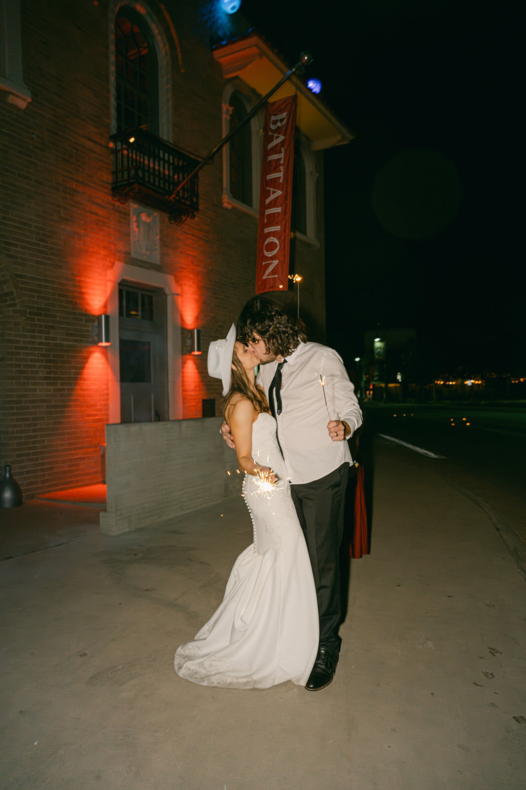 Bride and groom laughing during late-night party under streetlights