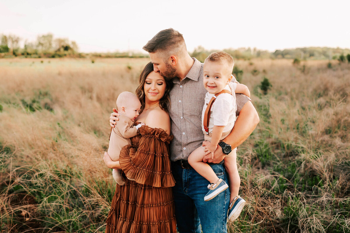 parents kissing holding kids during Springfield MO family photography session