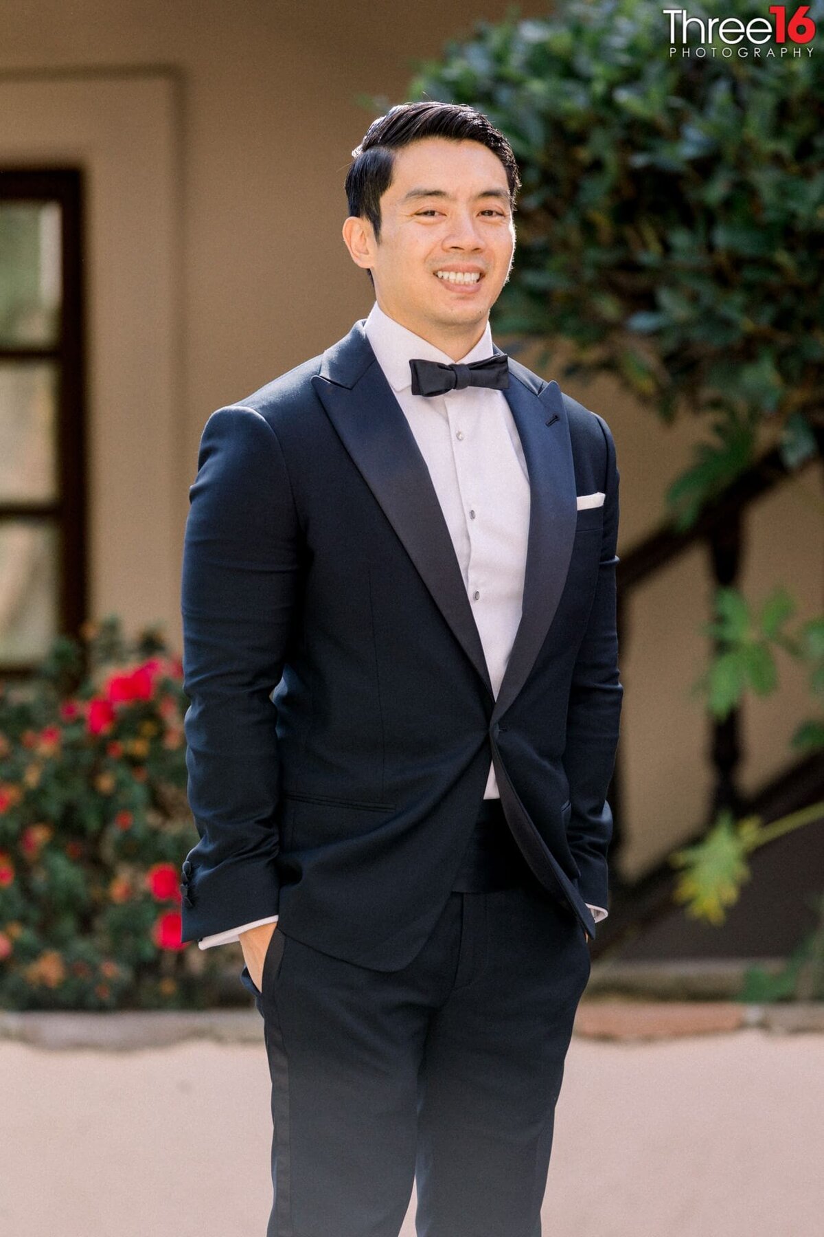 Groom poses in his tux and smiles before his wedding ceremony