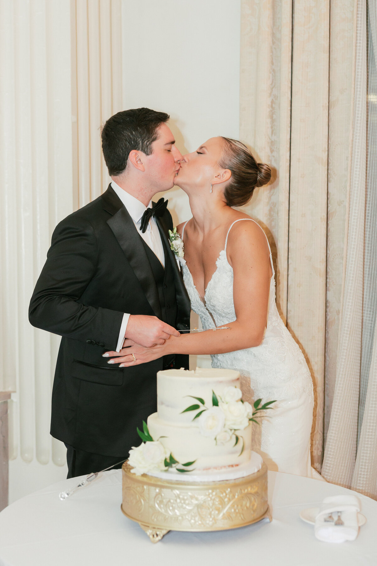 Bride and groom kiss during cake cutting at Philly wedding by a Philadelphia wedding photographer.