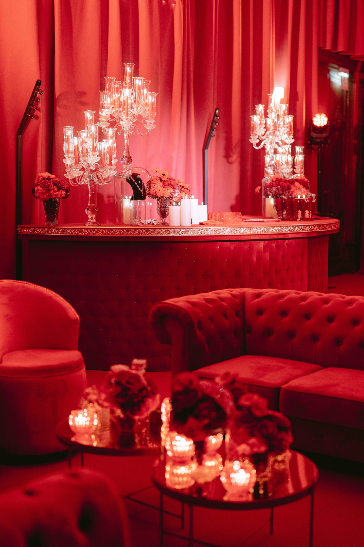 The stunning photo was captured at the enchanting Shangri La Hotel & Ritz Paris Hotel in the beautiful city of Paris, France. Renowned photographer Matteo Coltro skillfully composed and snapped this captivating image, showcasing a luxurious red-themed lounge. The space features plush tufted red sofas and a sophisticated round bar adorned with exquisite crystal chandeliers. Bathed in warm, ambient lighting, the room exudes an air of opulence and refinement. Tables adorned with tasteful floral arrangements and flickering candles further enhance the elegant and cozy ambience of this exquisite setting.