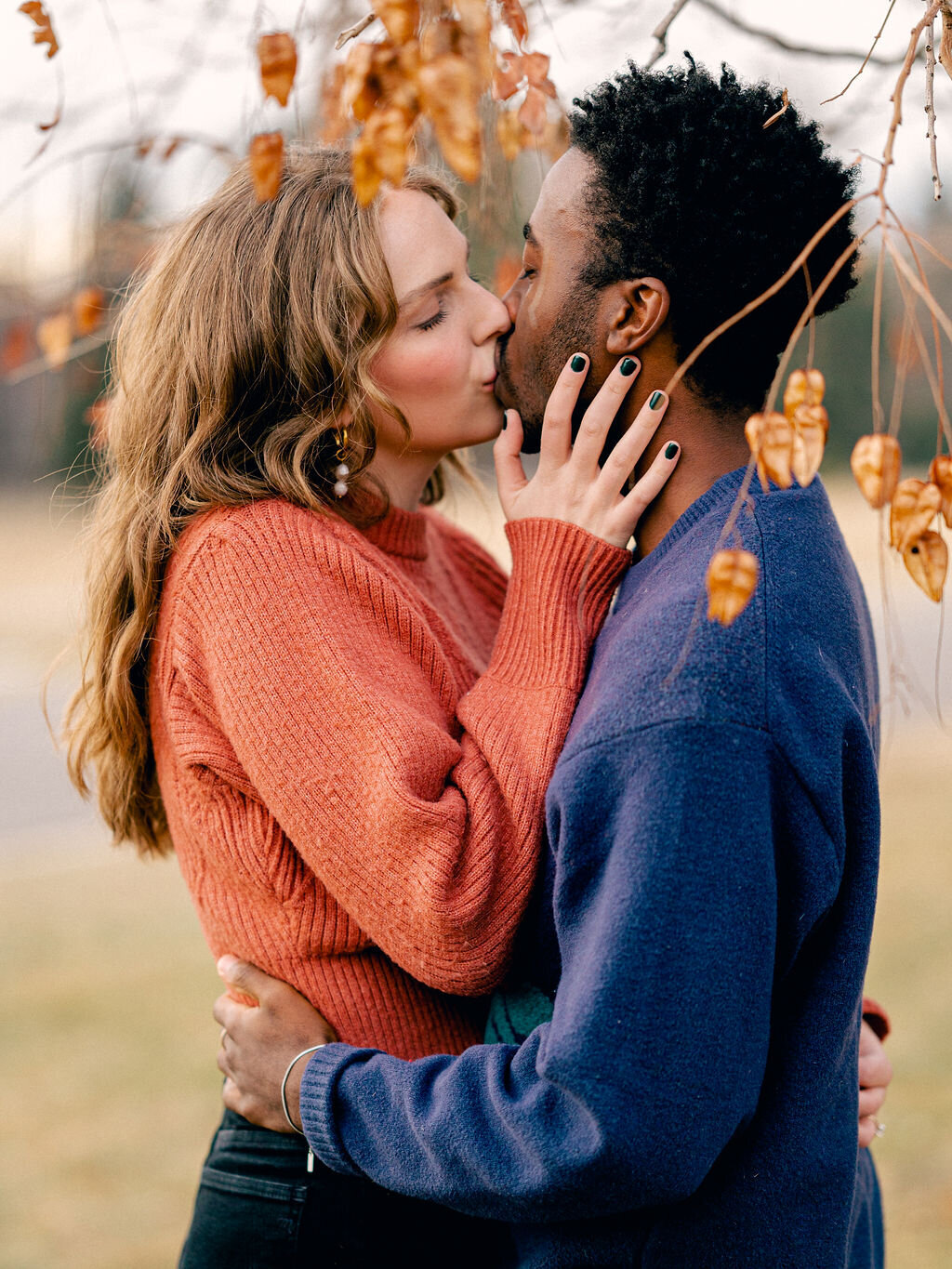 A couple kisses under a tree at Cheesman Park in Denver, Colorado