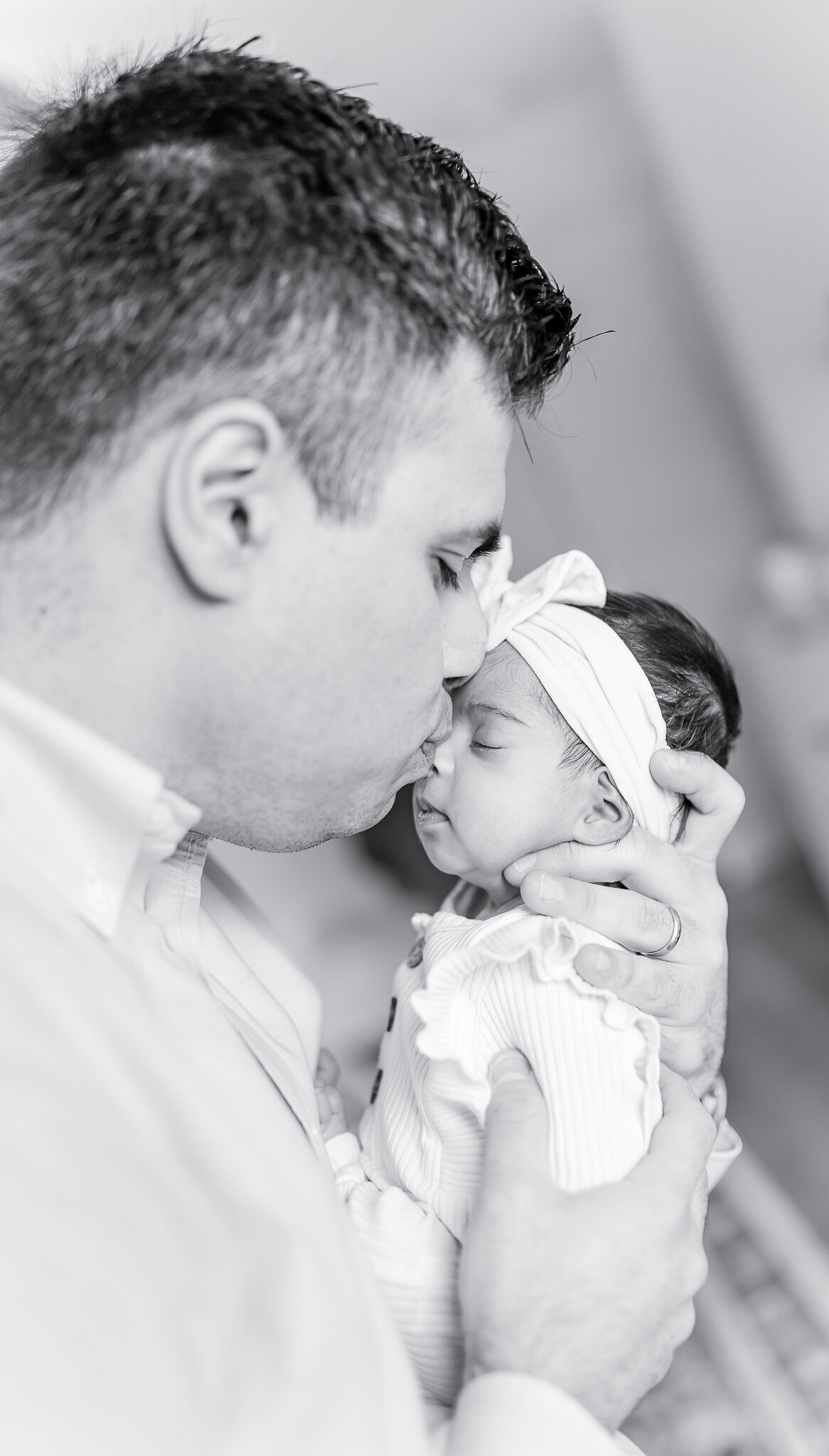 Heartwarming father-daughter moment in a natural light newborn photography session. A dad tenderly cradles his baby girl, showcasing the deep bond and love between them.