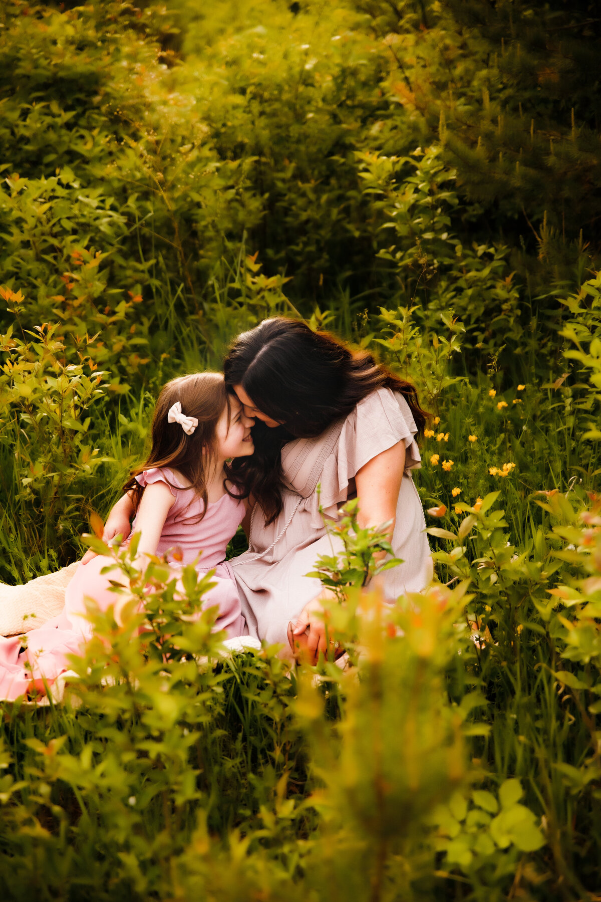 mother and daughter snuggling in the grass of a Skaneateles field