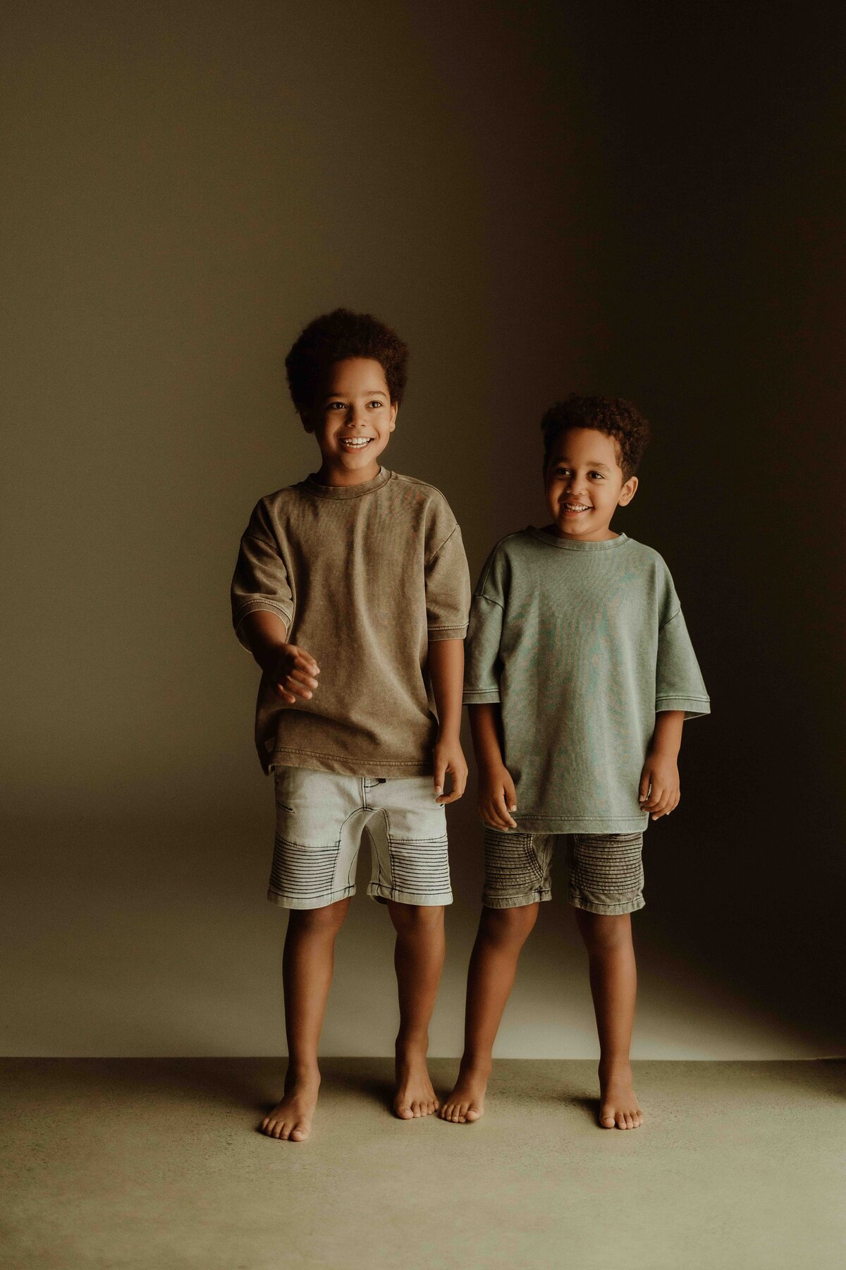 Two toddlers standing in a studio photoshoot.