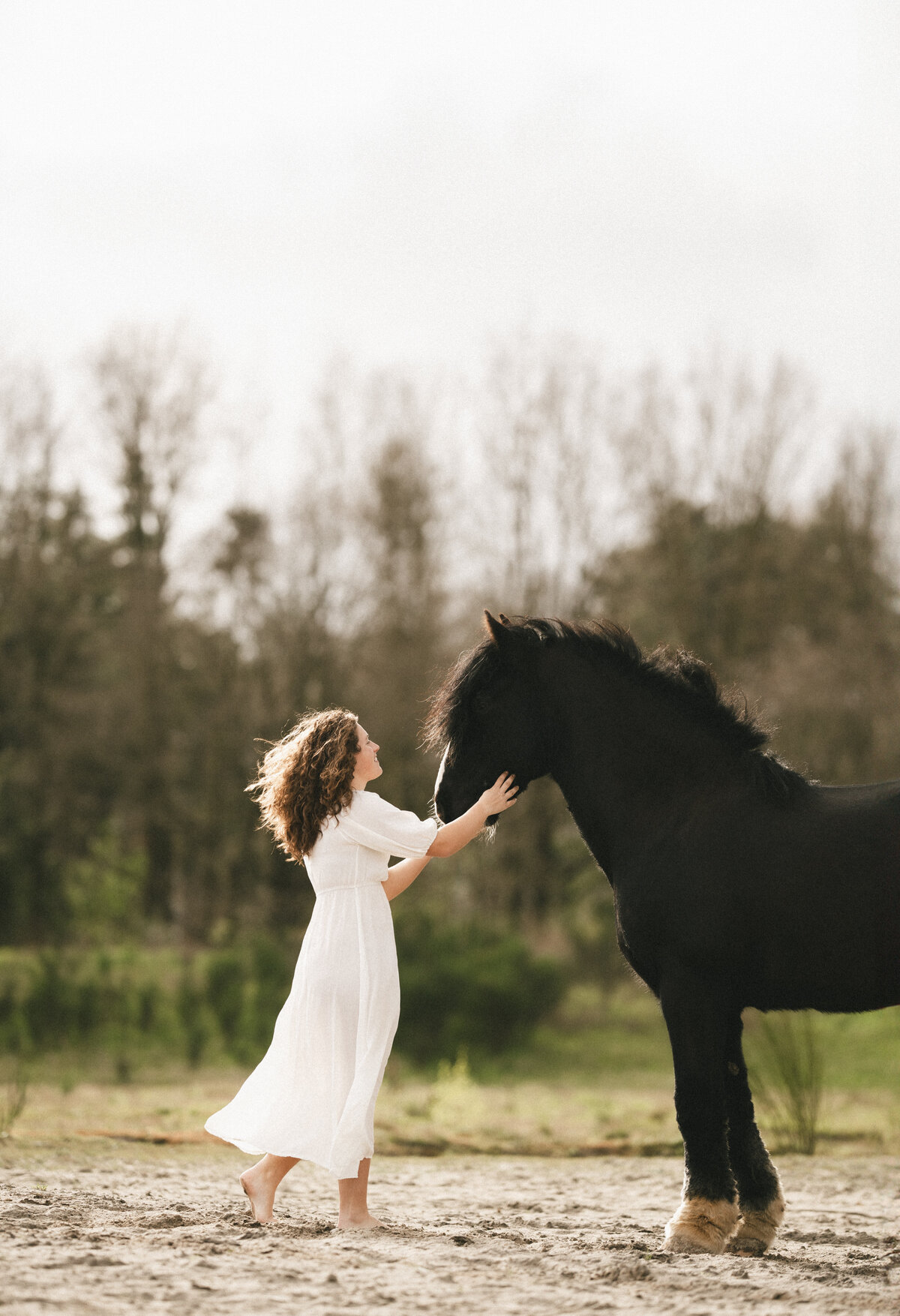 Cinematische fotoshoot van Vera en haar paard met focus op zachte lichtinval.