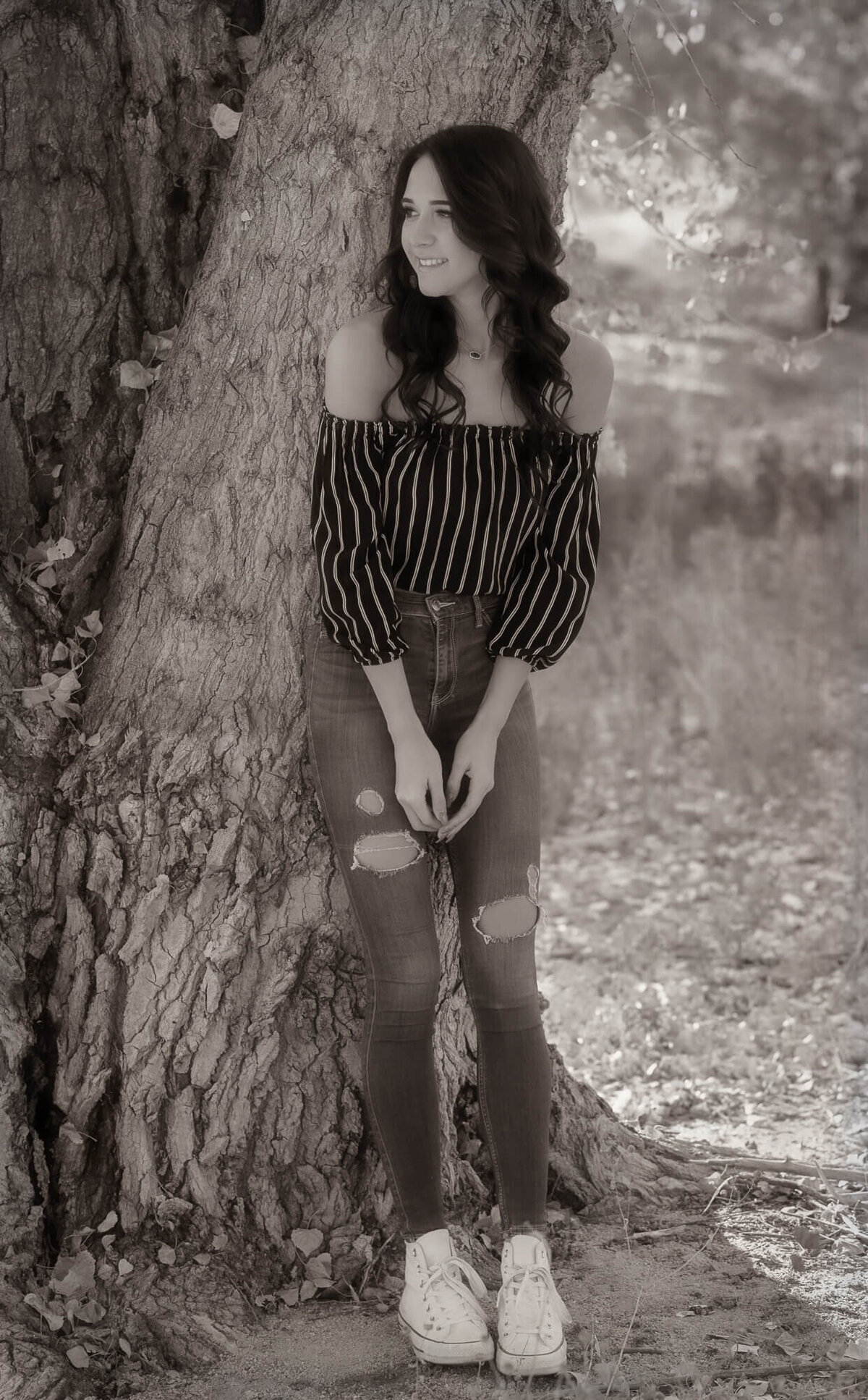 Girl poses against tree in Prescott senior photography session with Melissa Byrne