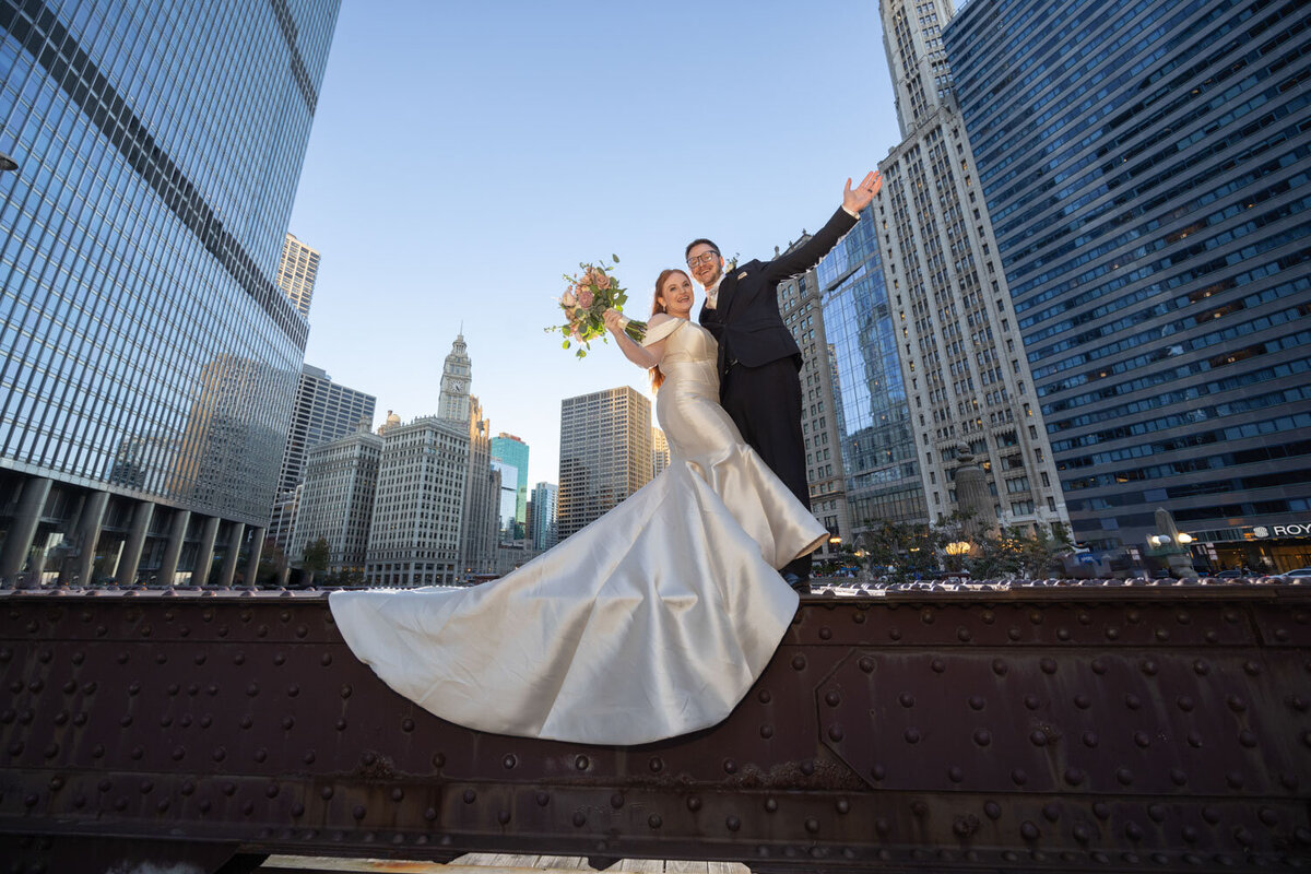 A bride and groom are posing for a picture in front of a city skyline
