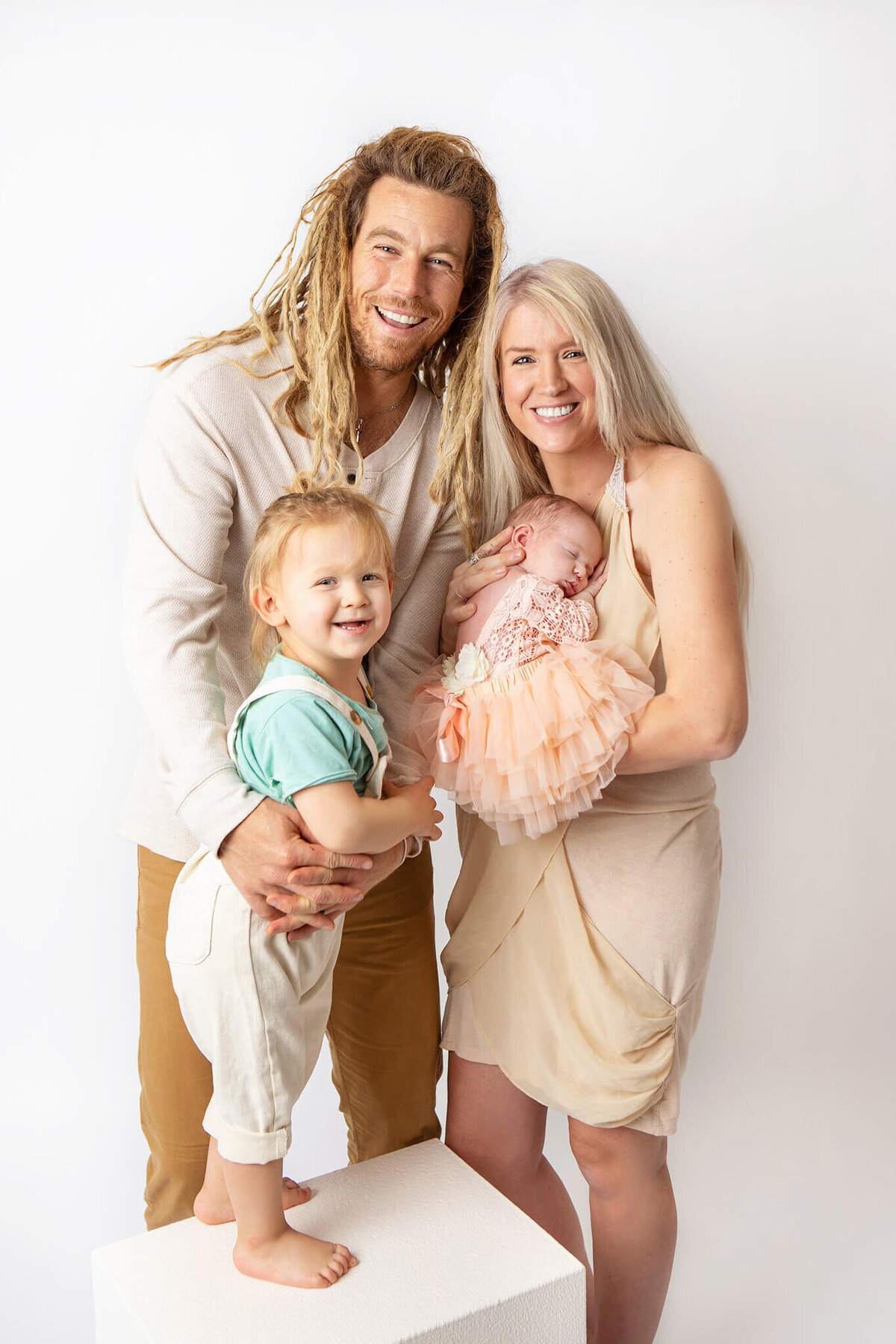 A happy family of 4 in Los Angeles smiling with their newborn baby daughter by Los Angeles newborn photographer