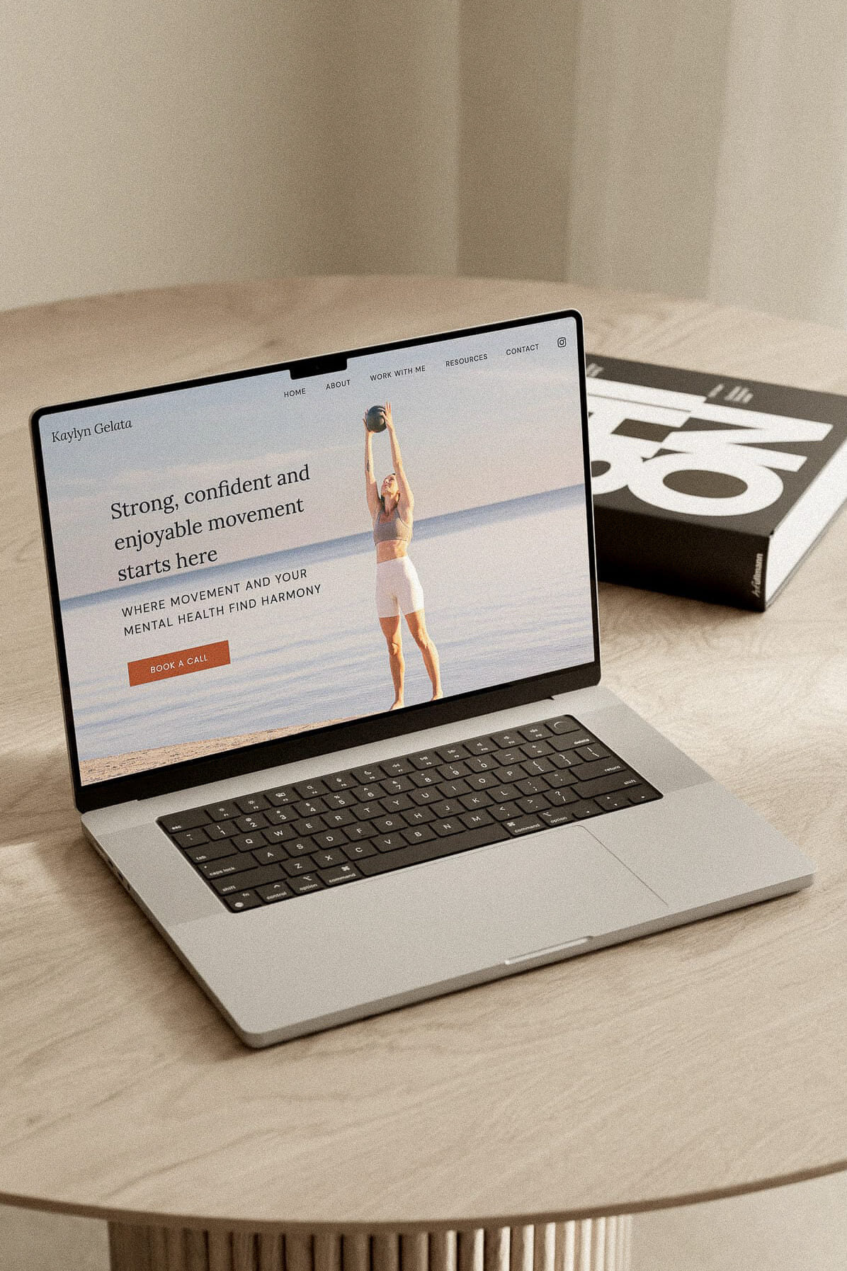 Mockup of a custom Showit website for a yoga and Pilates instructor, displayed on a laptop. The design emphasizes strength, movement, and mental health with a calming beach background