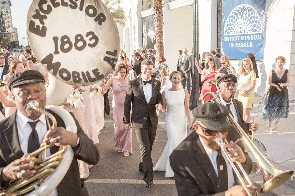Newly married couple walks to the wedding reception venue in a second line with the Excelsior Band, established in 1883 in Mobile, Alabama.