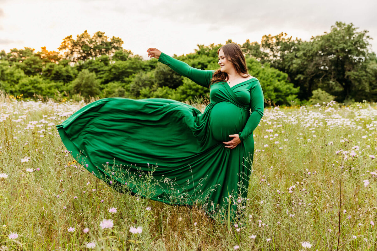beautiful pregnant woman throwing her gown into the wind in a field in Green Bay