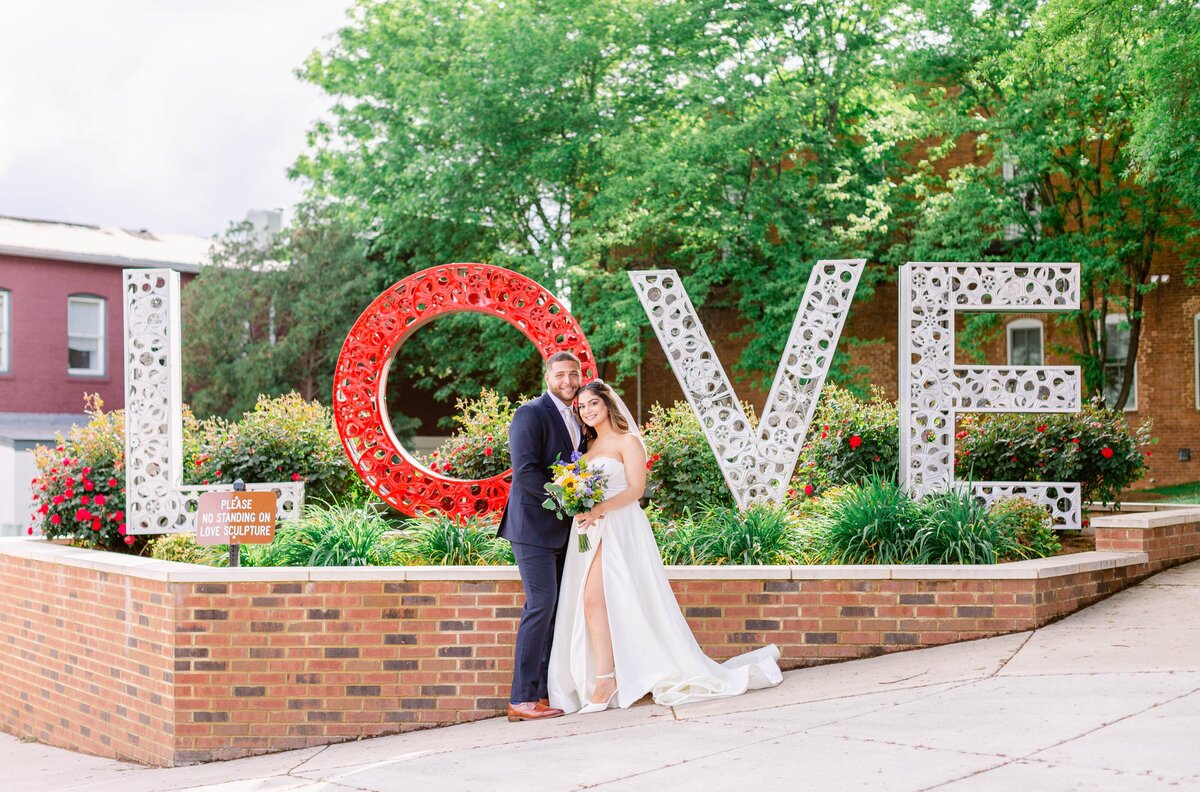 Bride and groom standing in front of Love Sign in Culpeper, Virginia. Captured by Bethany Aubre Photography.