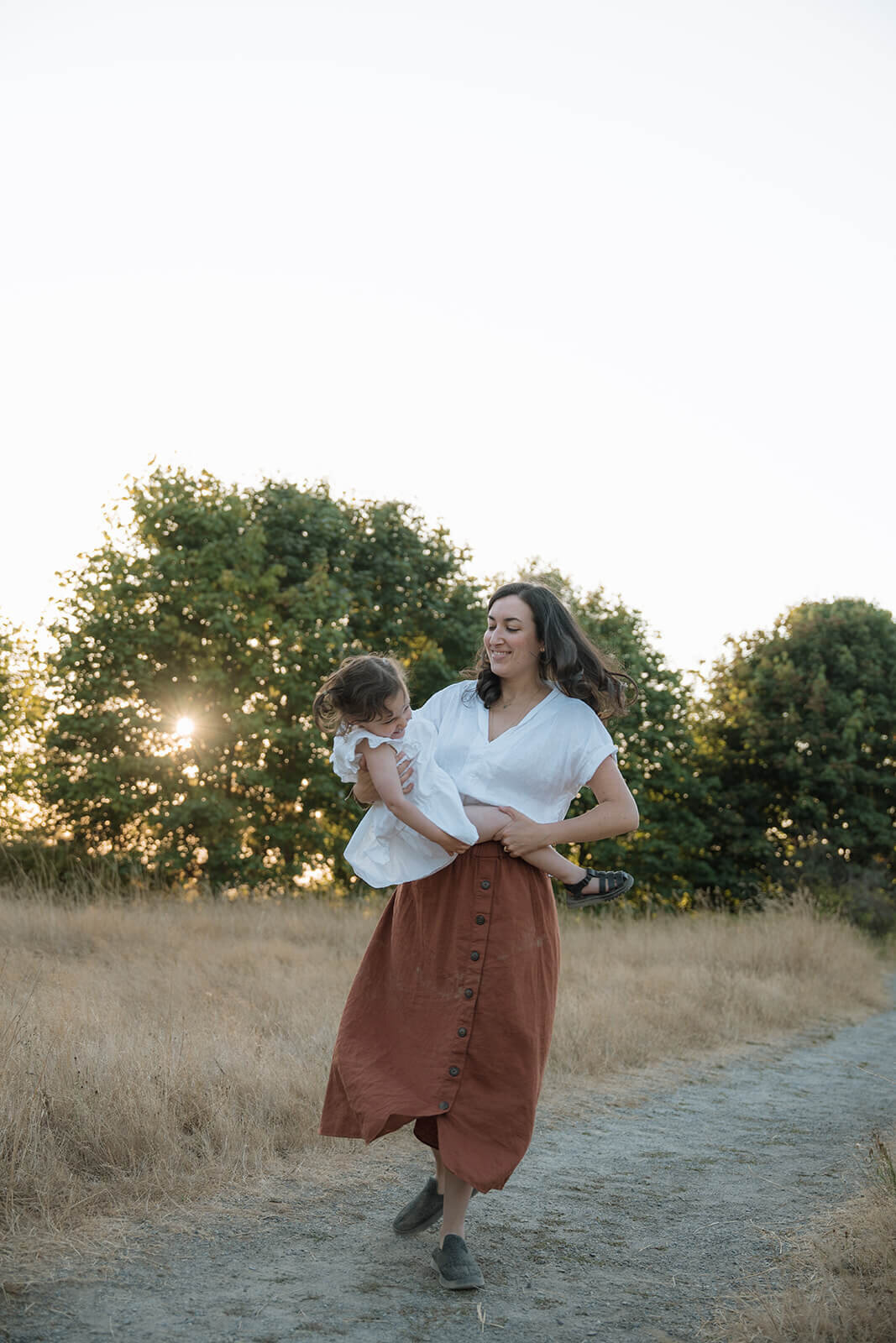 mother spinning with daughter outdoors at golden hour