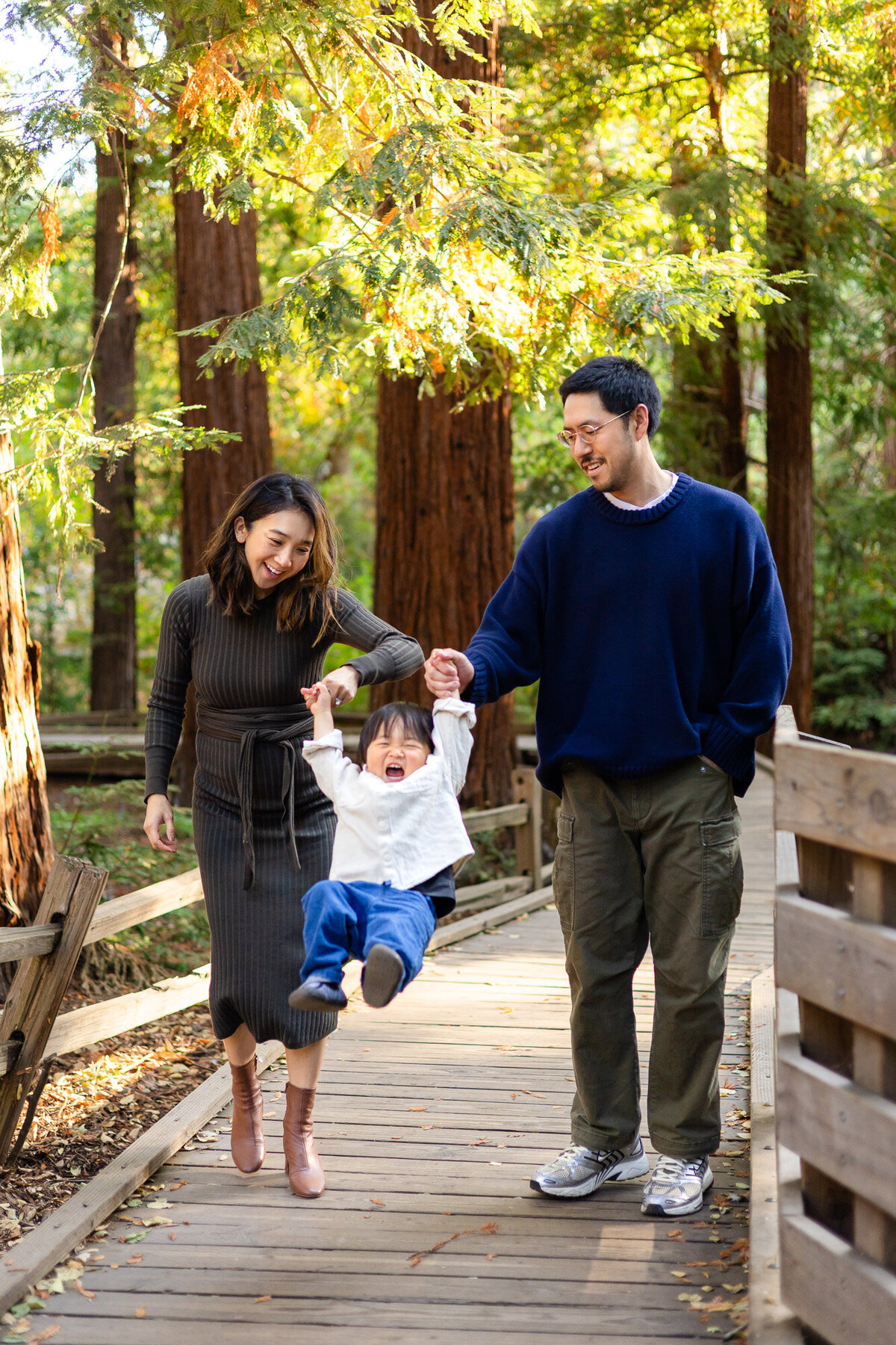 Parents swinging toddler between them on a wooden path in nature – Bay Area Family Portfolio | Ellobelle Photography