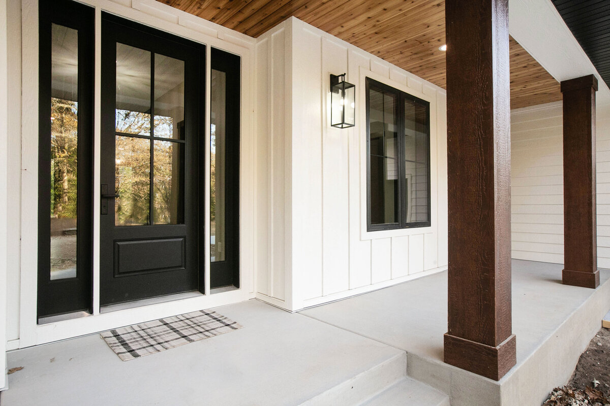 Exterior view of custom home in Big Lake Township, Minnesota with farmhouse details, cream siding, wood pillars and front porch built by Cornerstone Custom Builds