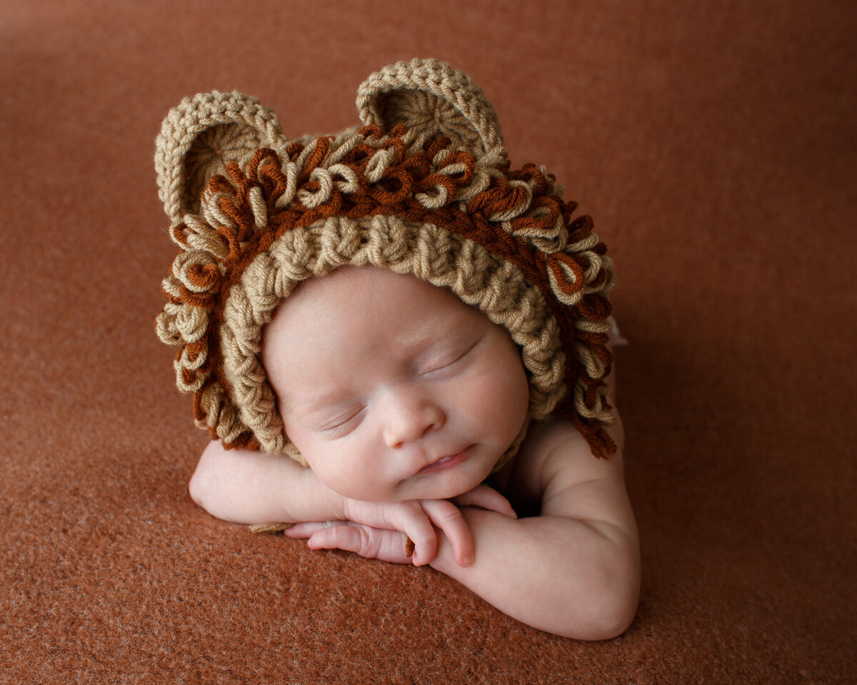 Cute close up of a tiny infant wearing a knit cap crochedt to look like a lion mane and ears