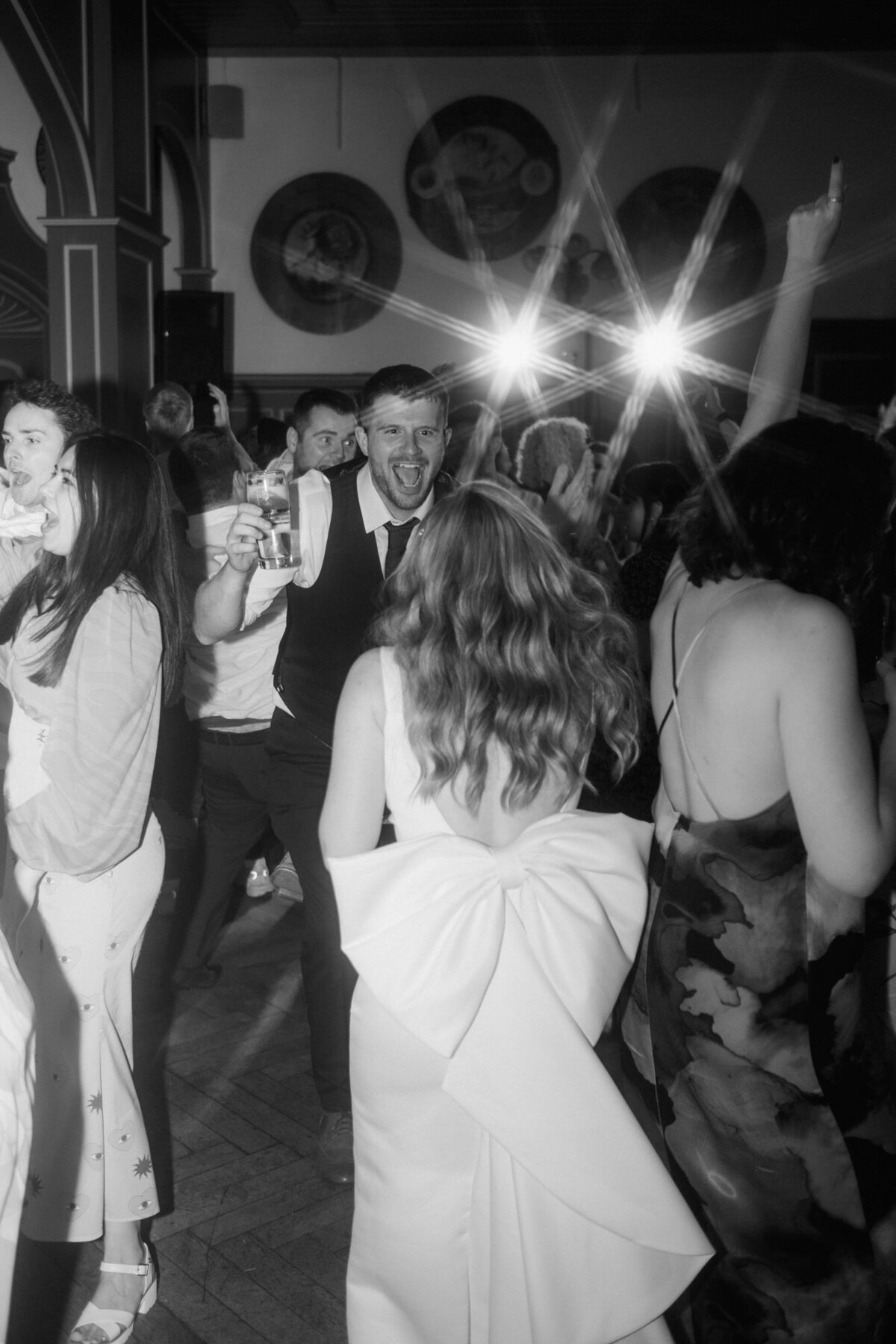 Die von hinten abgebildete Braut tanzt mit ihren Gästen.