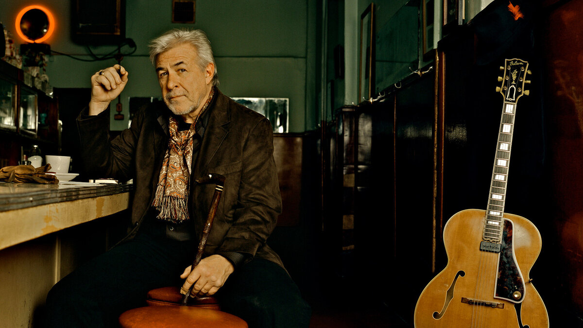 Country Music Portrait Jim Byrnes sitting at diner counter with guitar beside him