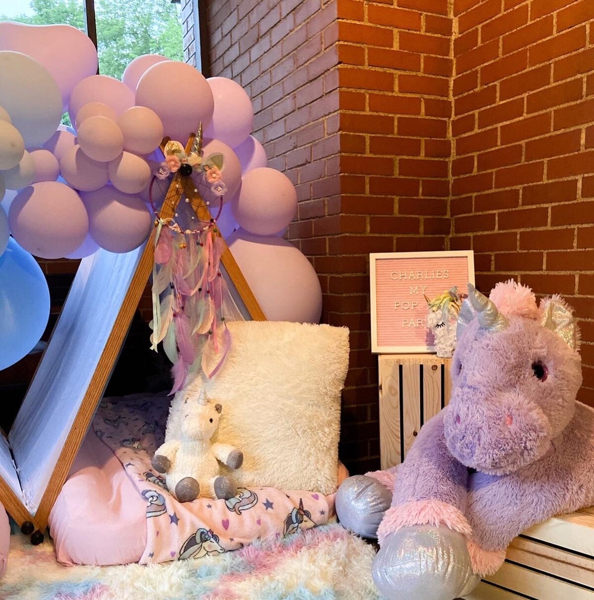 Purple tent with balloons and unicorn for girls birthday party