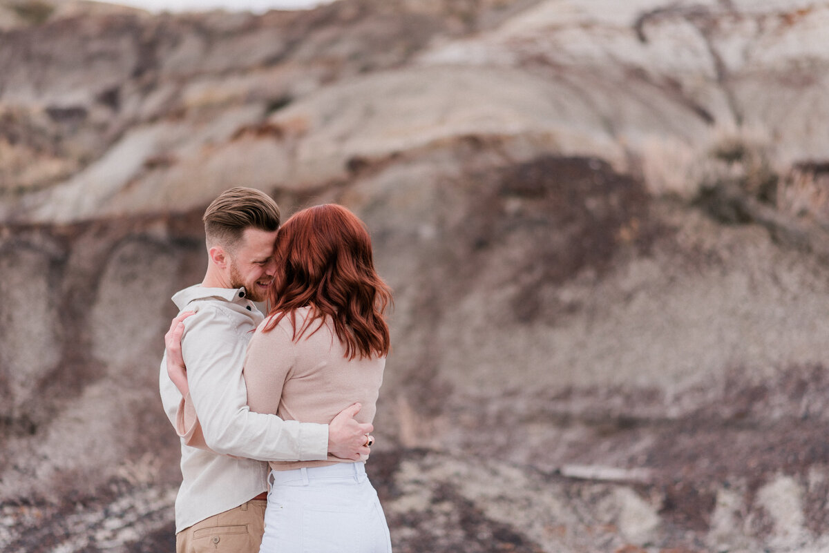 Gorgeous couple embraces, wearing neutral colours in the Badlands.