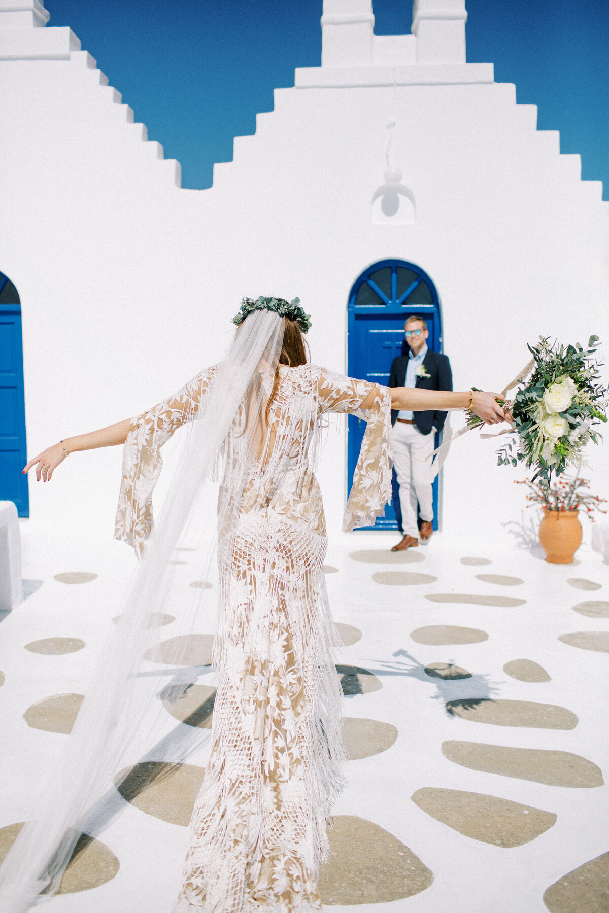 Bride dressed in rue de seine bridal gown walks toward her husband in Mykonos