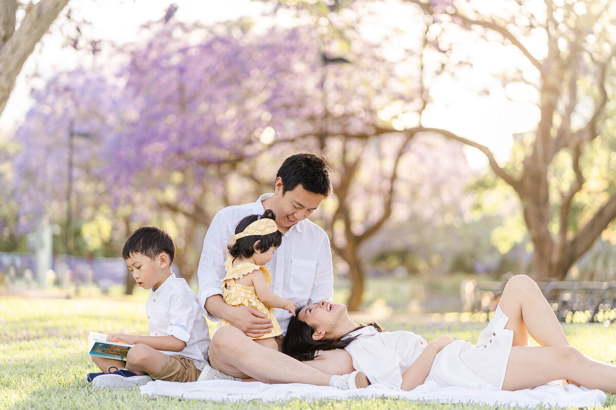 candid family shot of mum looking at dad love soaked family photo in spring blossoms in Brisbane