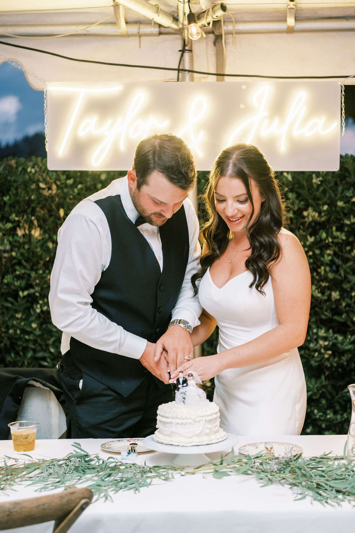 A bride and groom cut their wedding cake at their outdoor reception.