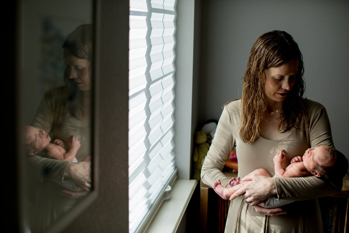 a mon in a dress looks down at her newborn baby boy