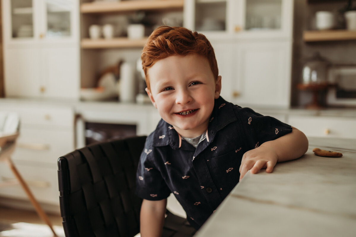 Toddler boy is excited to eat a cookie at a kitchen island