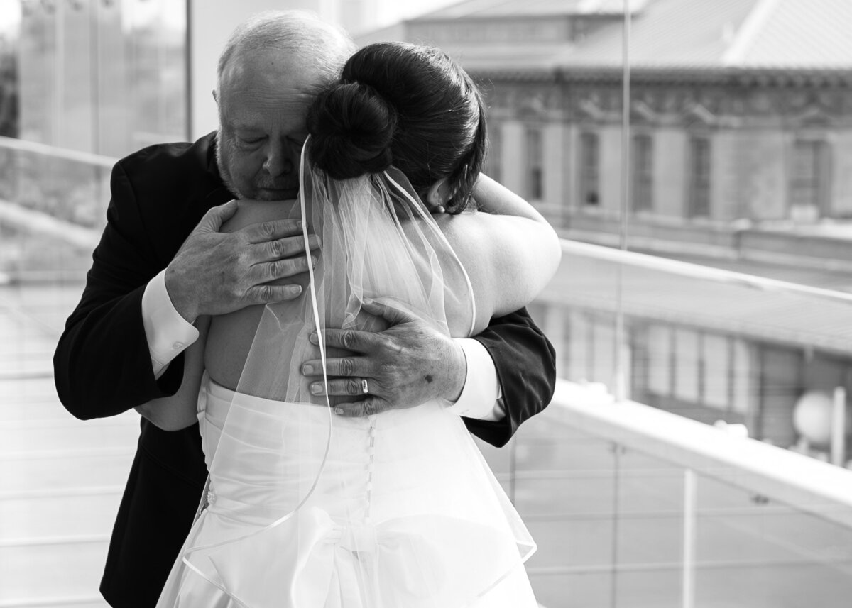 bride and father hugging after father sees bride in her wedding dress for the first time.