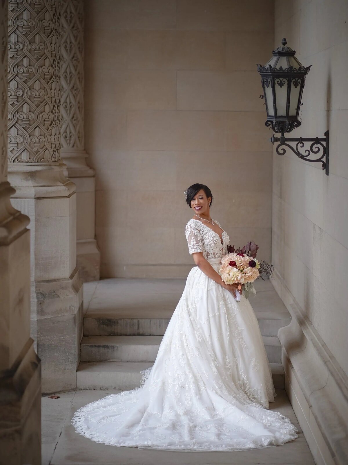 A bride standing in front of a small staircase holding a bouquet of flowers