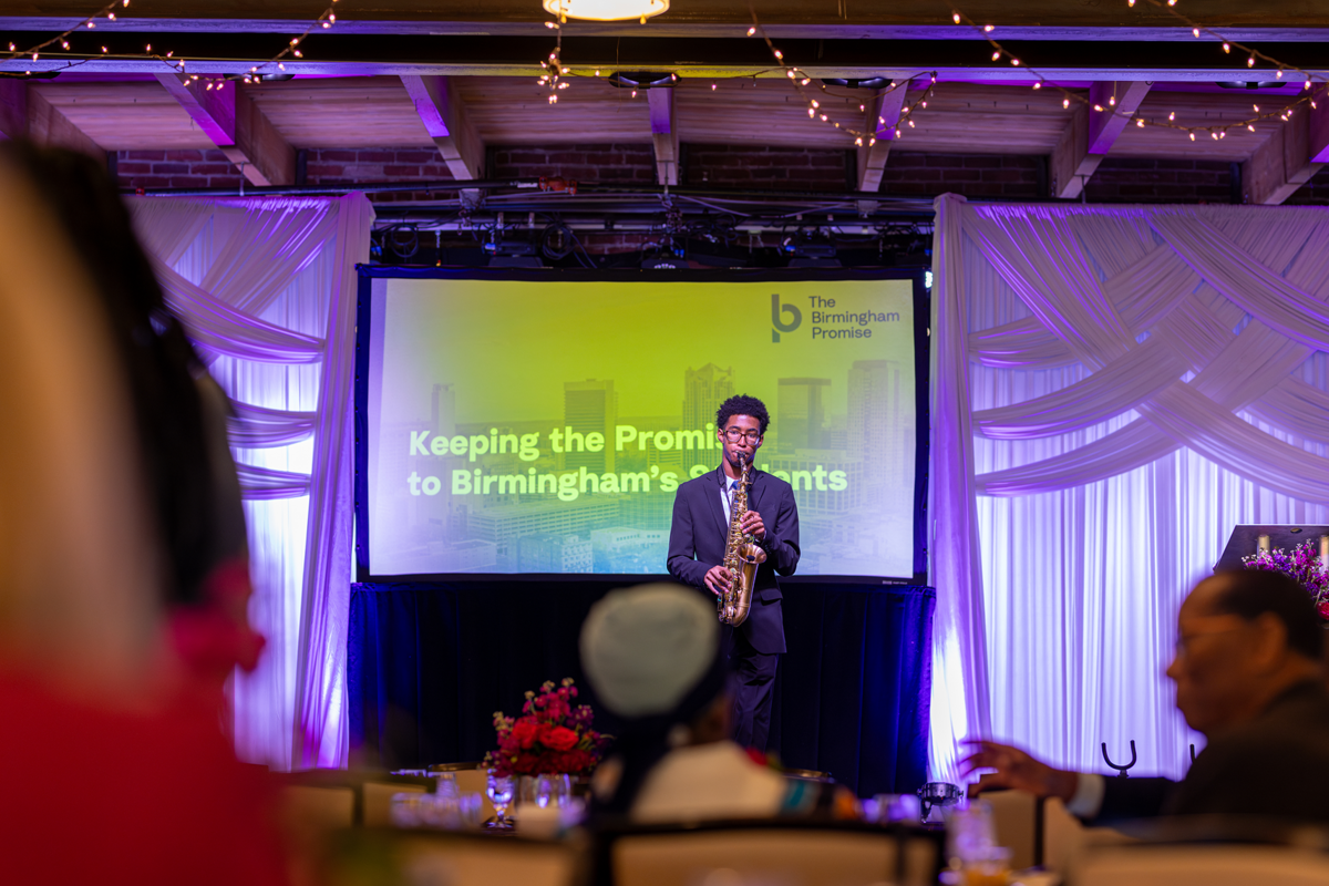 Young man playing instrument on stage for a Birmingham Promise event