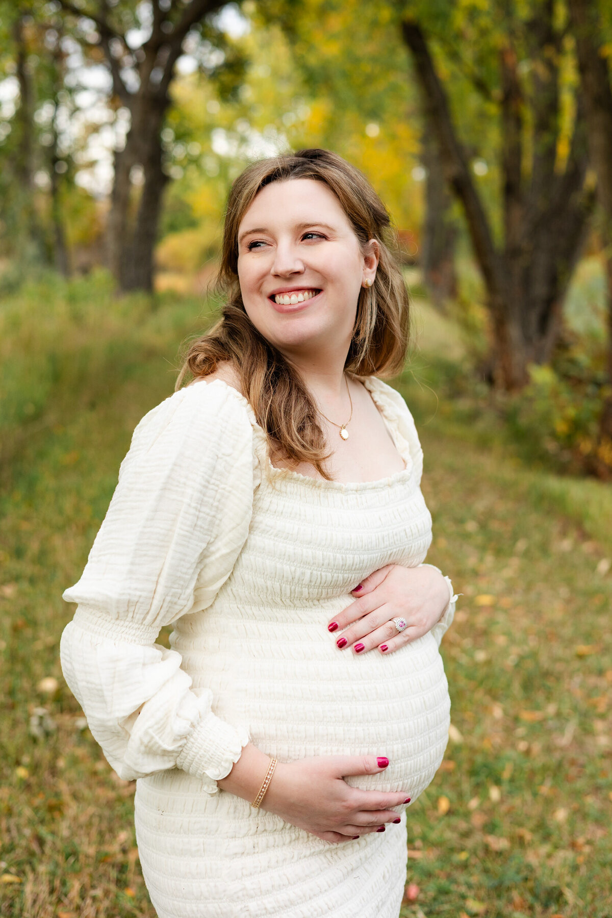 Pregnant woman holding her bump and smiling over her shoulder.