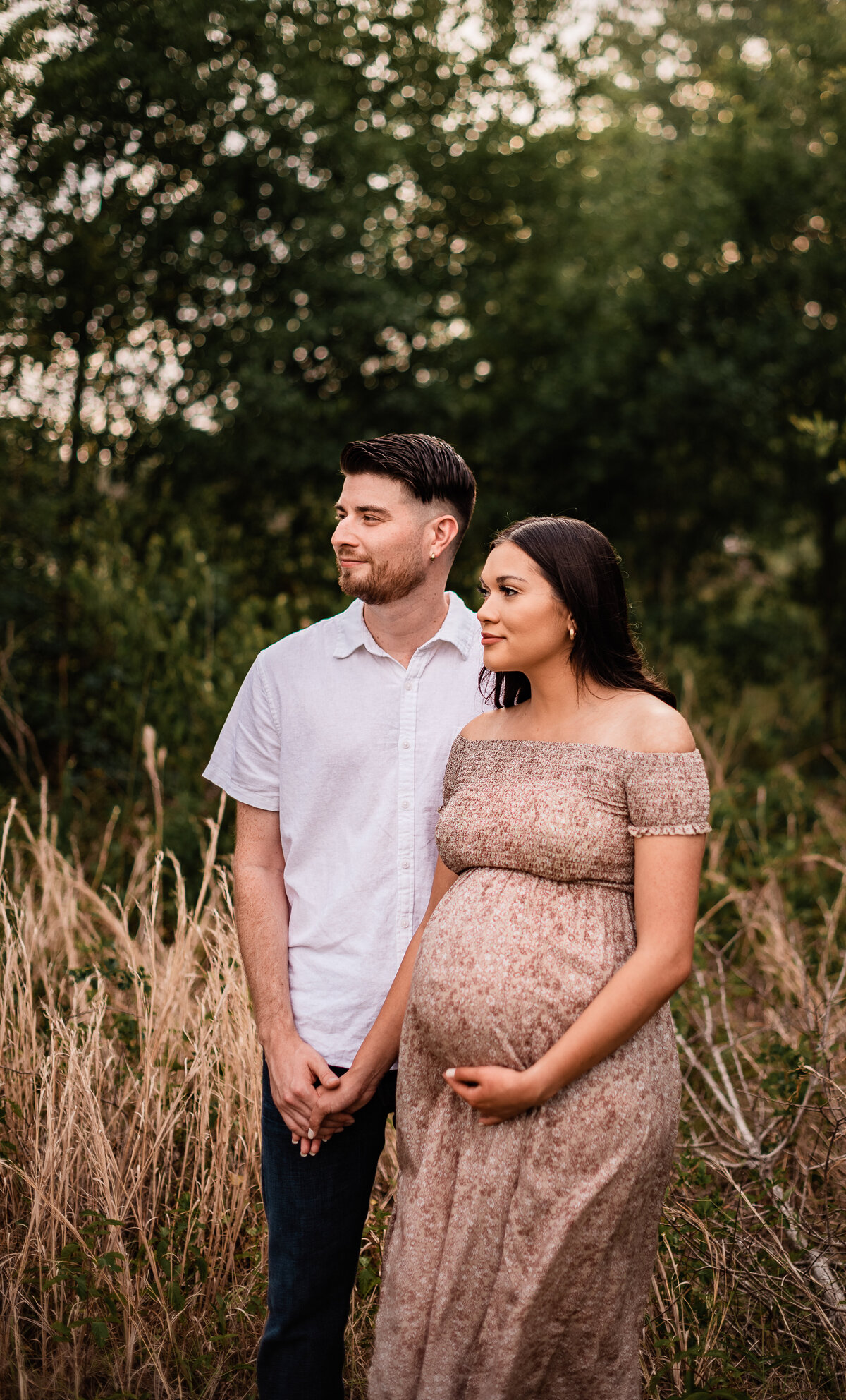 A Houston area mama to be holds her boyfriend's  hand and her belly as they both look into the distance.