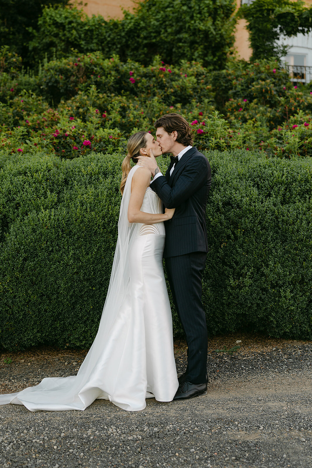 Bride_And_Groom_Kissing_In_Front_Of_Hedge