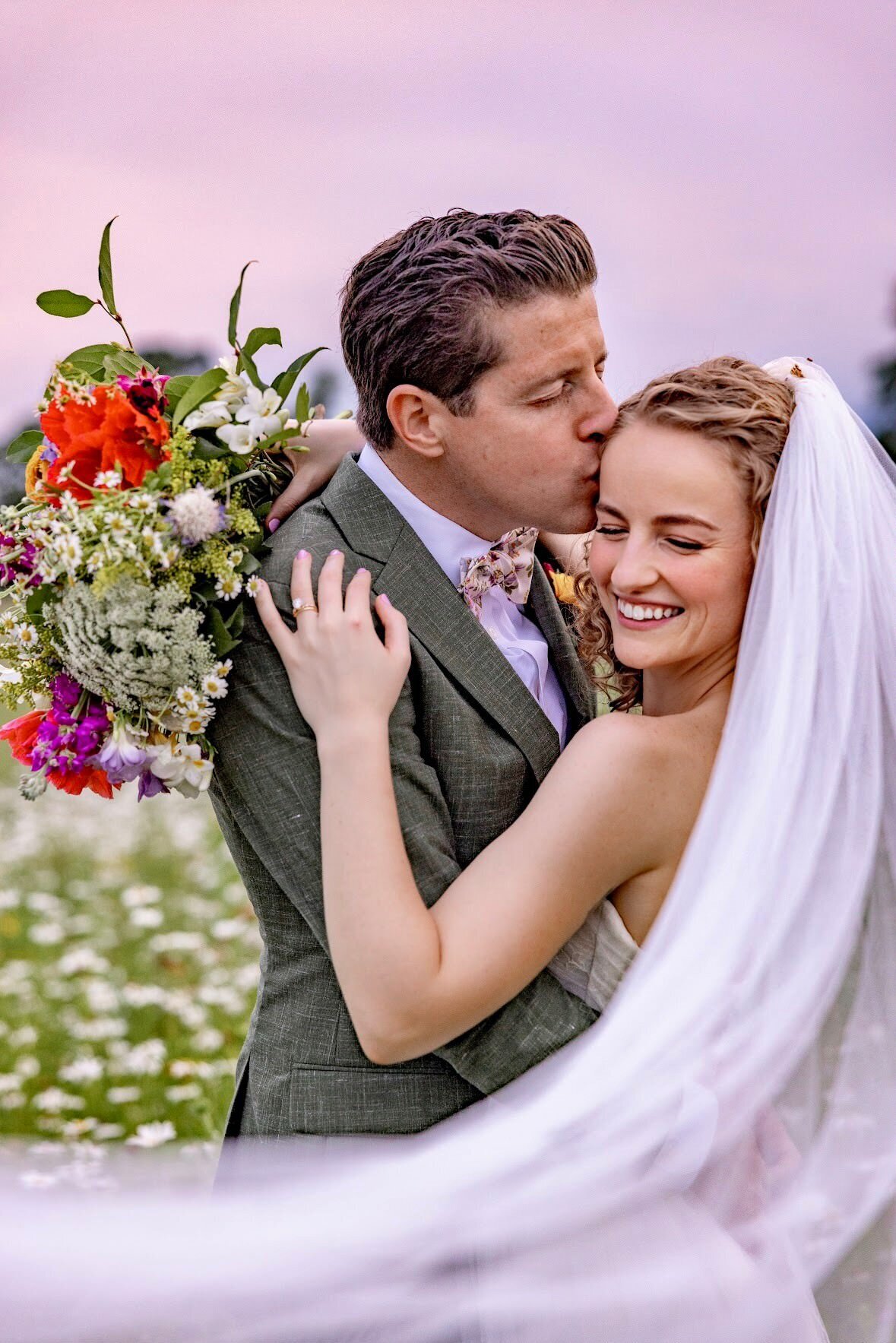 A bride and groom pose in a field of wildflowers