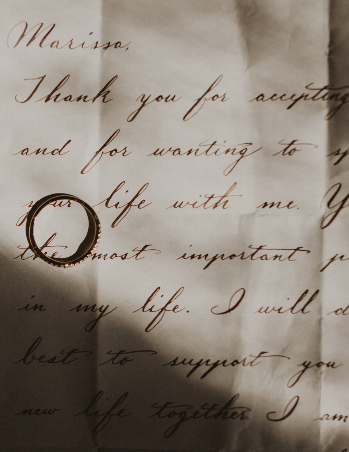 Ring sits on hand-written love letter on  paper with fold lines