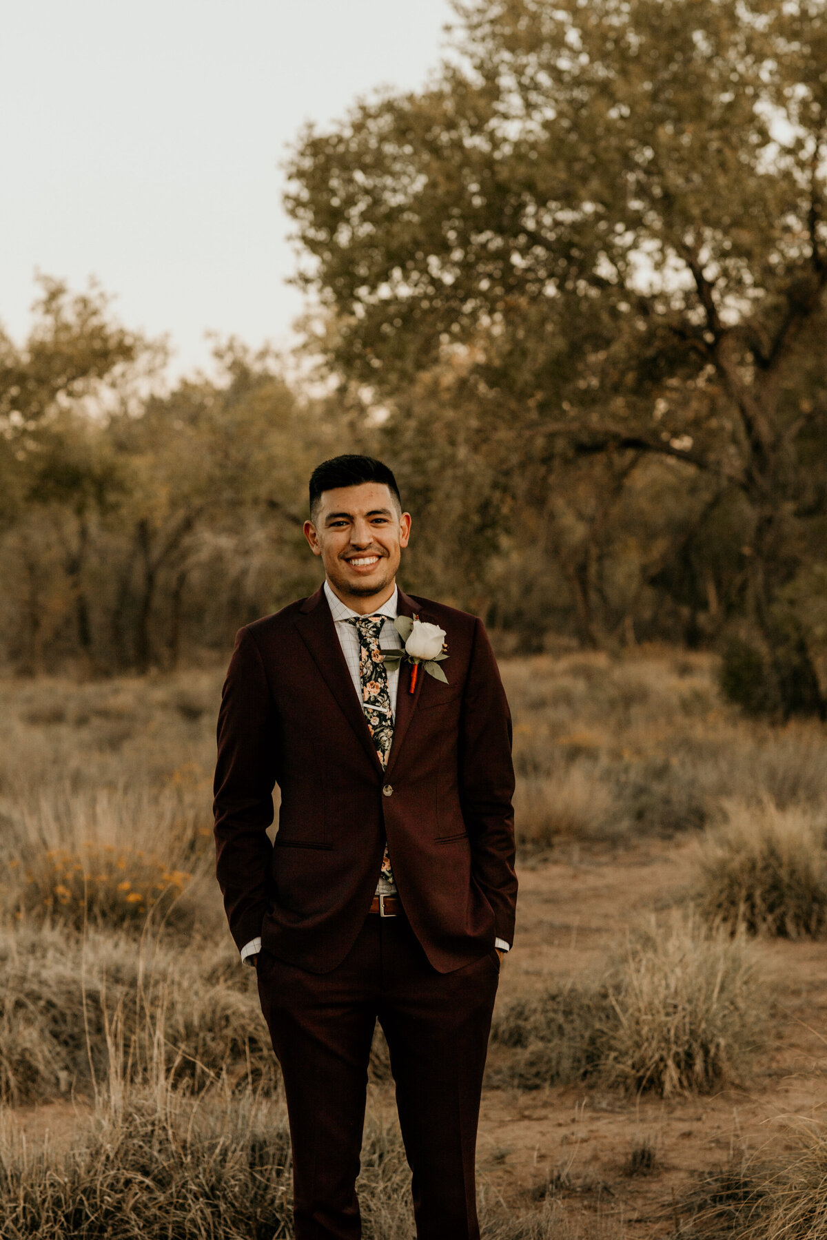 groom in a maroon suit standing in the desert