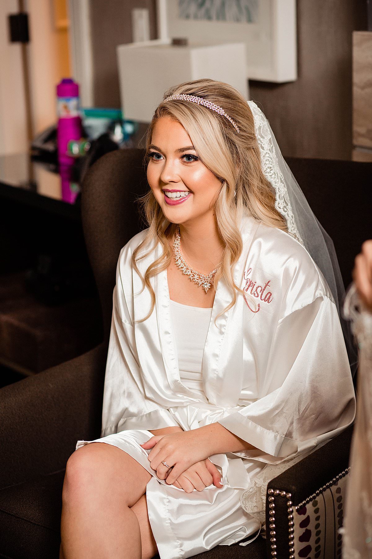 Bride wearing her custom wedding robe and veil waiting to get into dress
